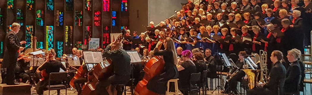 Spires Philharmonic Orchestra & Chorus (Spires Music) pictured in front of the John Piper window and the west window of Coventry Cathedral