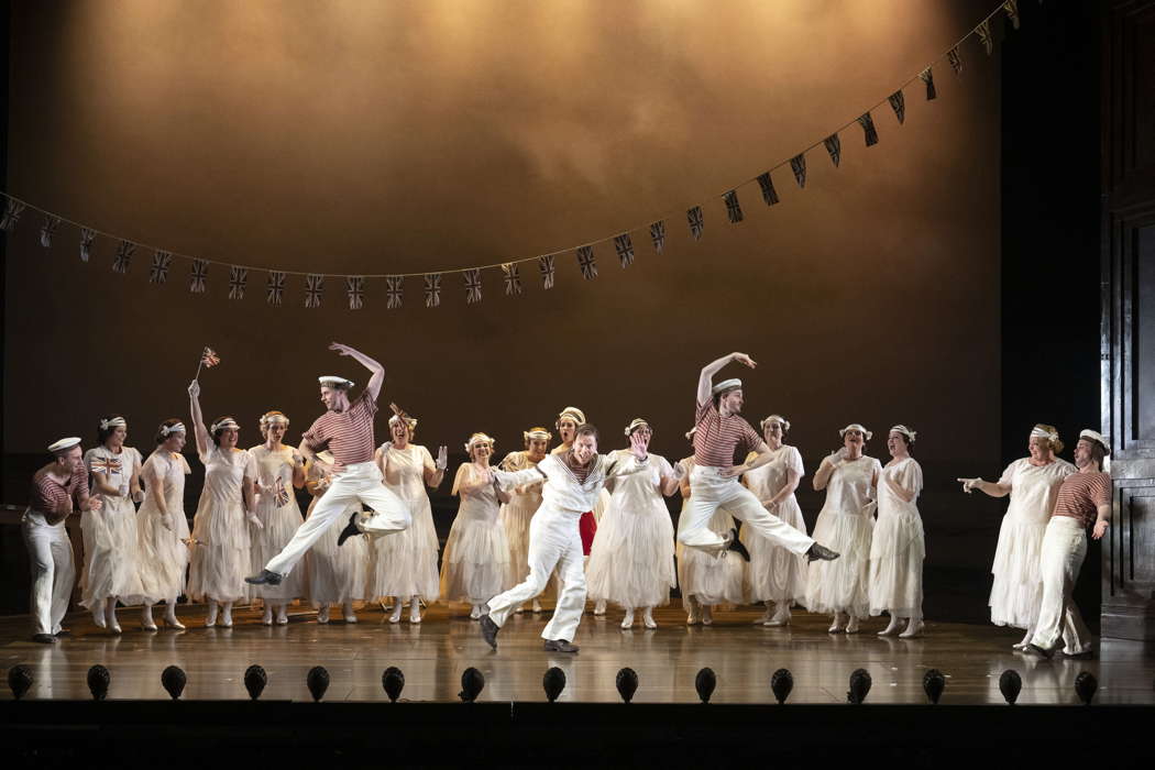 Xavier Hetherington as Richard Dauntless (centre) with dancers George Bishop (left), Ben Yorke-Griffiths (right) and members of the Chorus of Opera North in Opera North's production of Gilbert & Sullivan's comic opera 'Ruddigore'. Photo © 2024 Richard H Smith