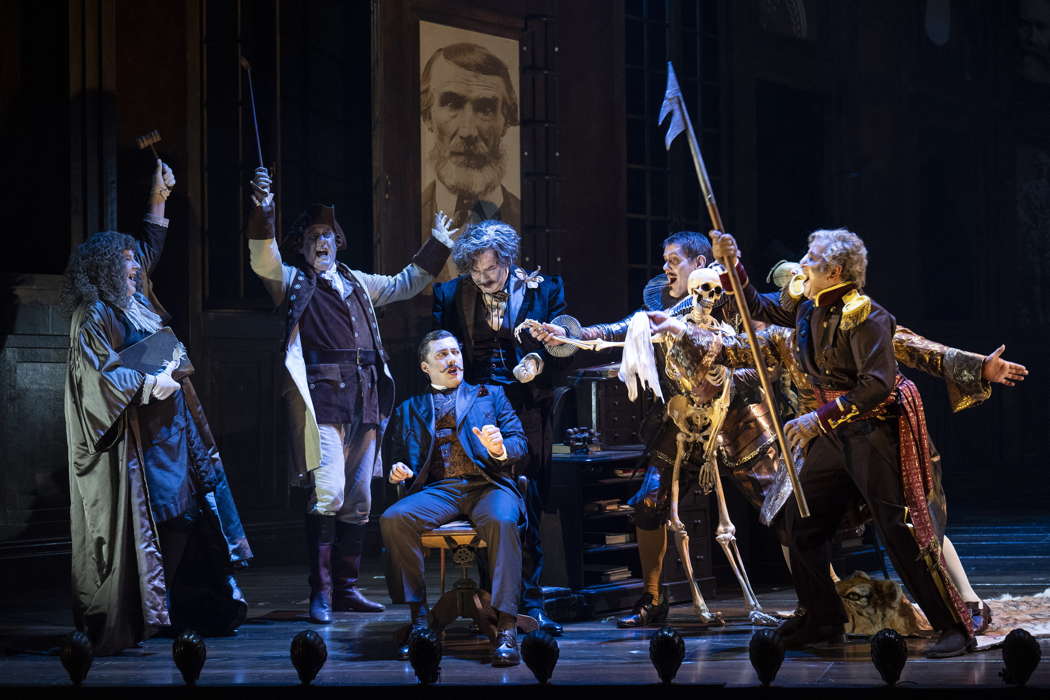 Dominic Sedgwick as Sir Ruthven Murgatroyd (seated) with members of the Chorus of Opera North as the ghosts of Ruddigore in Opera North's production of Gilbert & Sullivan's comic opera 'Ruddigore'. Photo © 2024 Richard H Smith